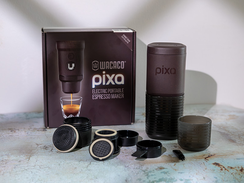 Wacaco Pixapresso (electric portable espresso maker) sitting on table with all the parts laid out, and the box in the background