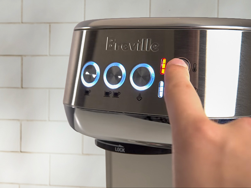 Finger pressing the milk temperature adjustment button on the Breville Bambino Plus