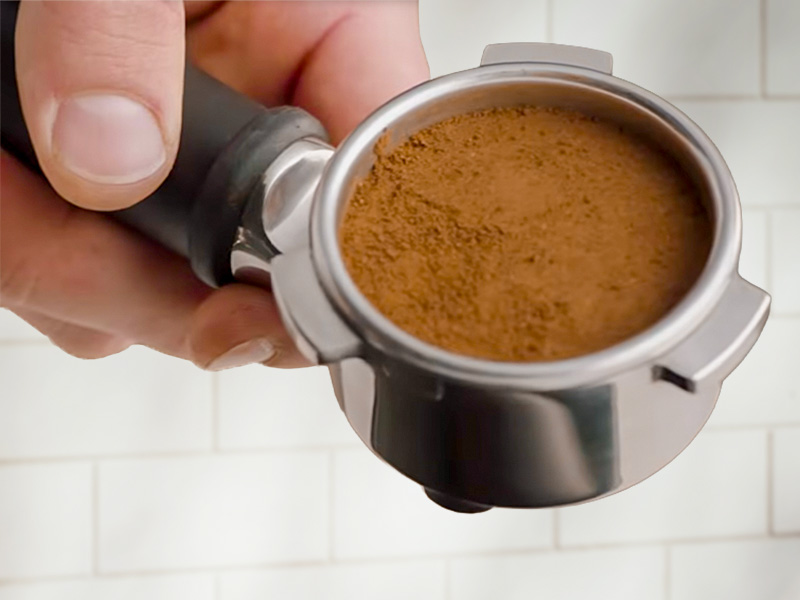 Hand holding a freshly prepared coffee puck towards camera