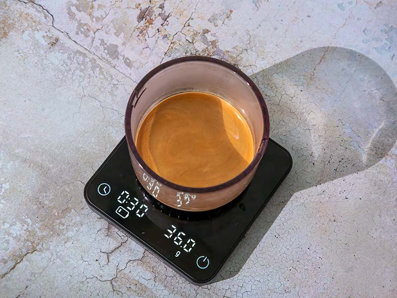 A fresh shot of espresso with crema sitting on coffee scale showing 30seconds, 36g