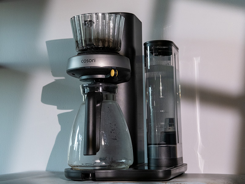 Cosori Juni, turned slightly towards the camera, carafe on the drip tray and grounds in the filter basket